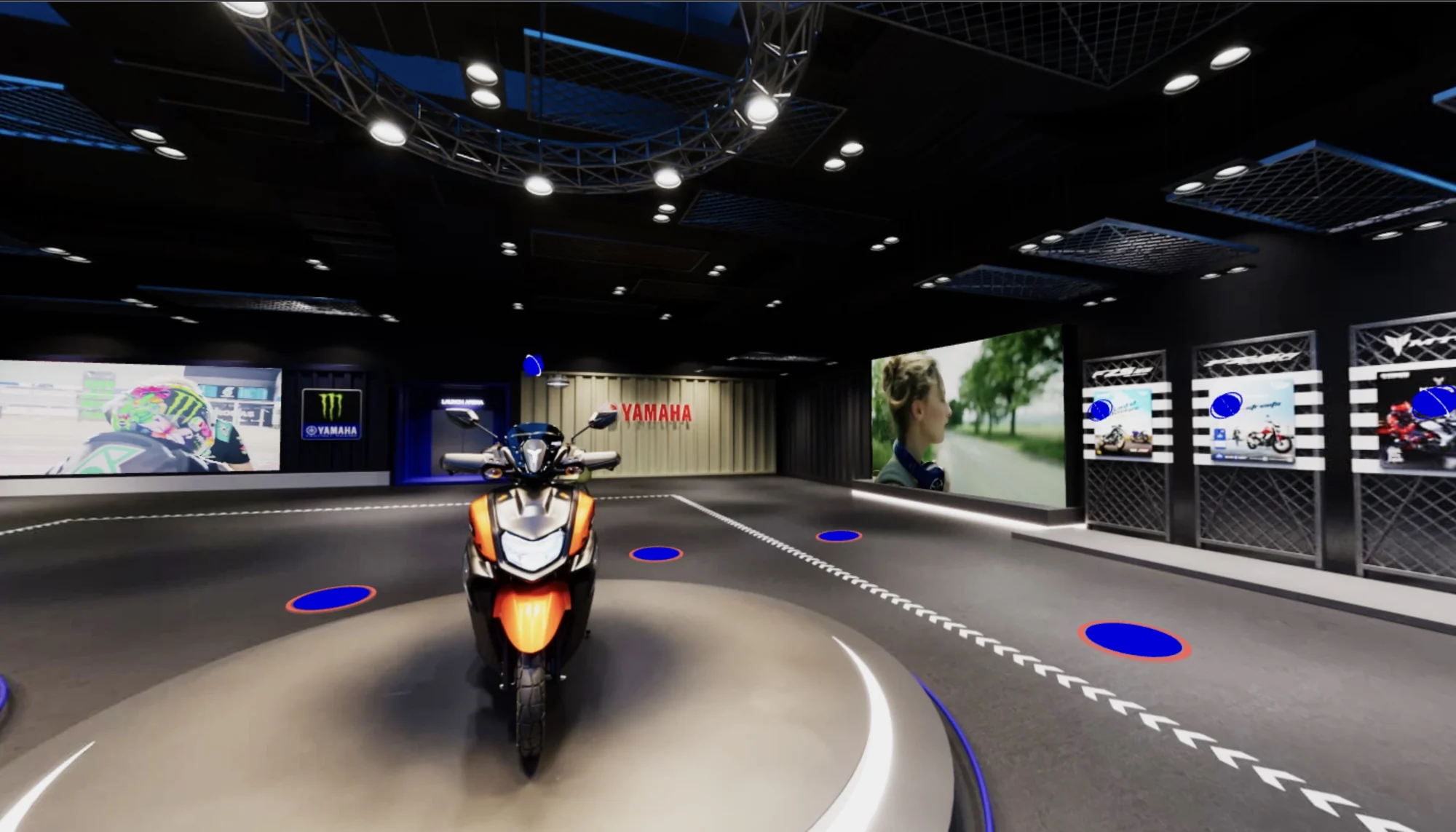 Inside the showroom: an orange Yamaha scooter on a lit turntable, with video walls and bike displays around it